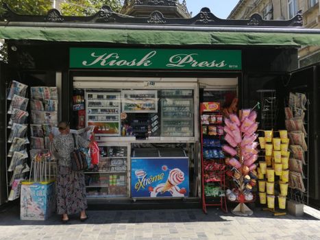 A woman shops at a kiosk selling newspapers and snacks in Azerbaijan. Marketing in American is mostly online.